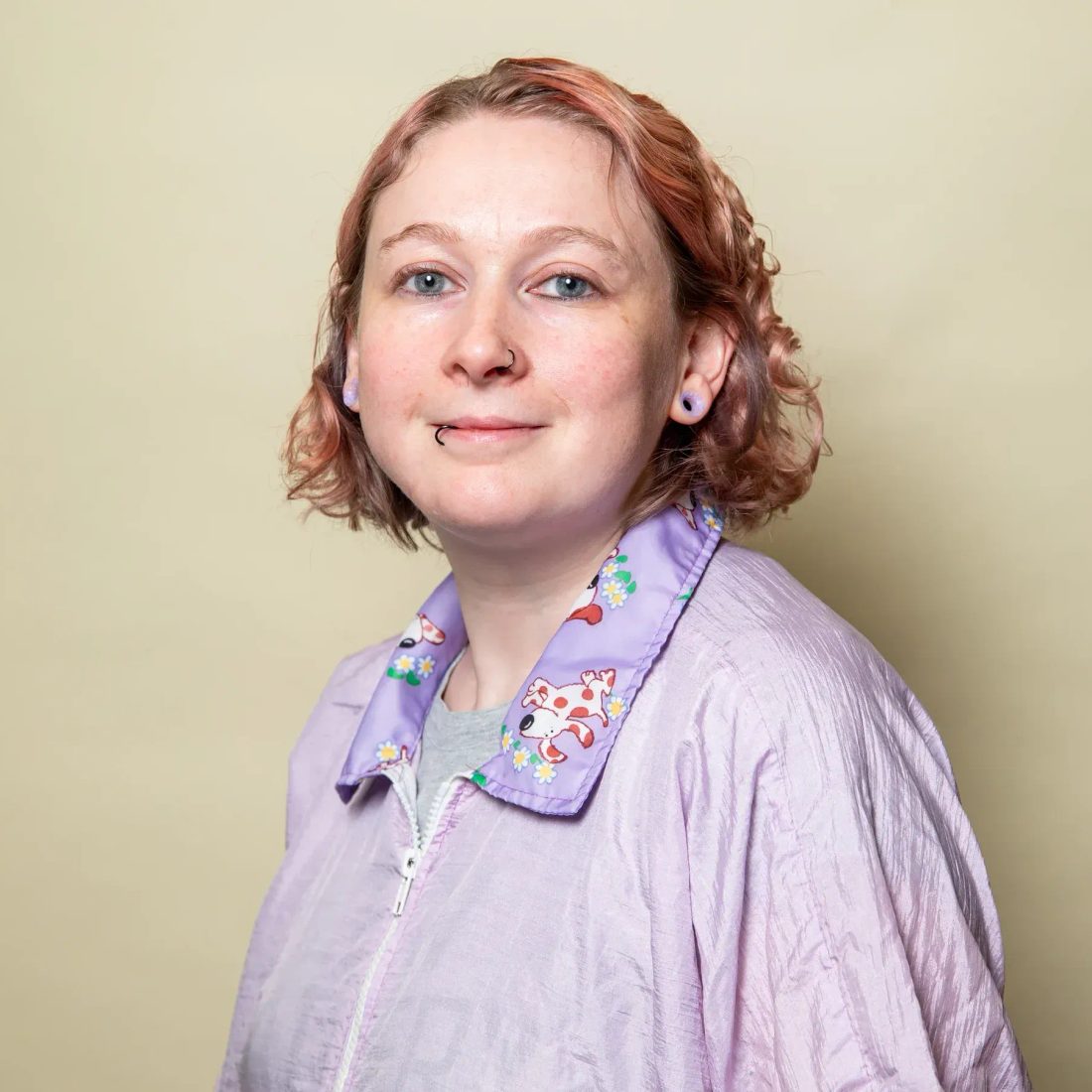 Woman with short reddish hair in purple jacket smiling